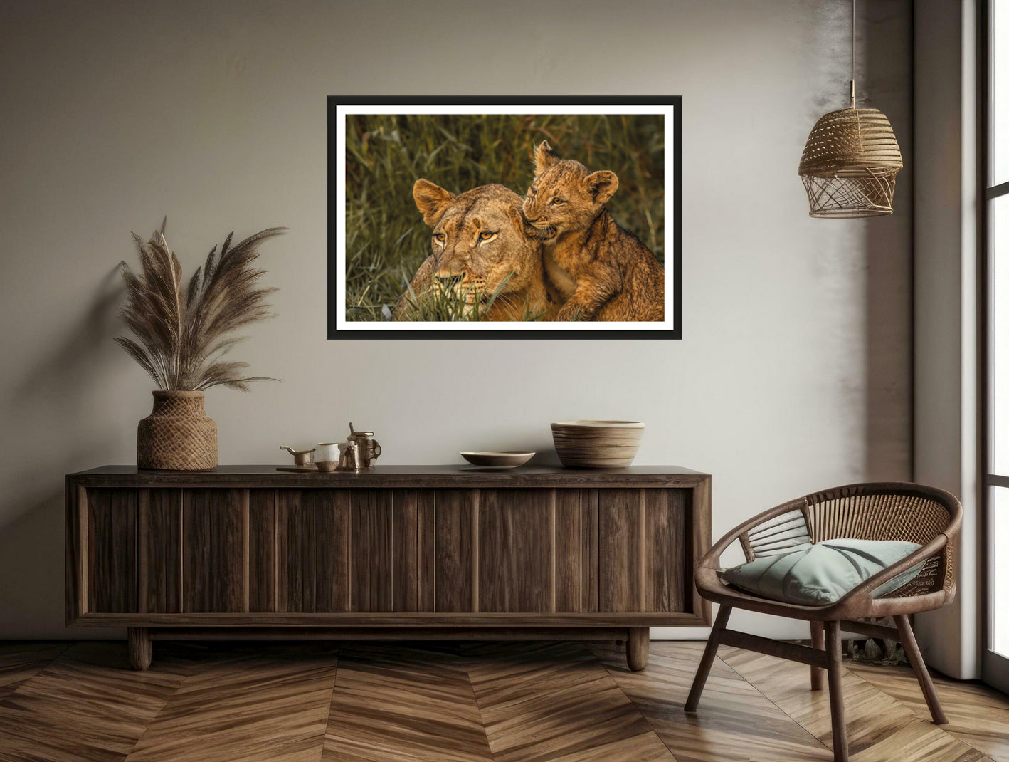 A photograph of a cute lion cub biting into his mother’s ear hanging on a brown wall above a commode and a chair next to it.