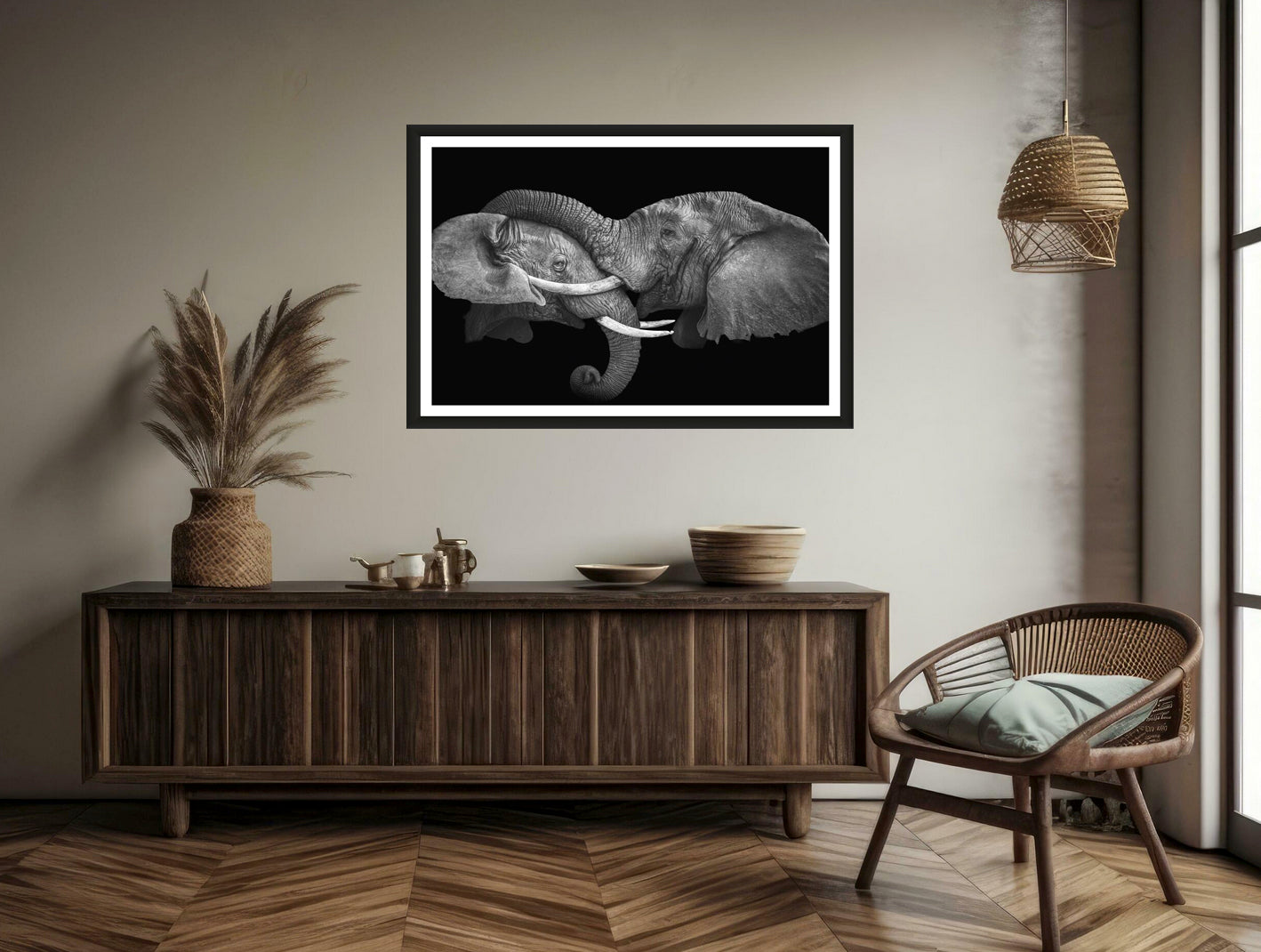 Photograph of one elephant having his trunk on the head of another elephant hanging on a white wall above a chair and a commode.